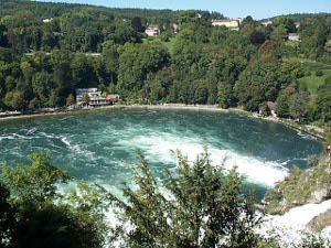 Looking down at the base of the falls one sees a dark blue green pool of water with two enormous fingers of white foam stretching out at the base of the falls
