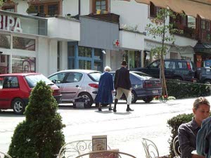 Up the shopping street of Maryhofen walk an elderly copy clad in typical Tyrolean costume; the man with boots and a jacket and Tyrolean hat, the woman in a long flowing Tyrolean coat