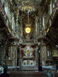 The interior walls, ceiling, gallery, and columns are ornately decorated and glittering in gold and silver.