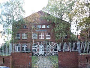 The three-story synagogue is located behind a brick wall topped with a white iron fence
