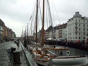 A line of masts stretches down the pier at NyHaven harbor, which is a narrow inlet flanked by streets and buildings