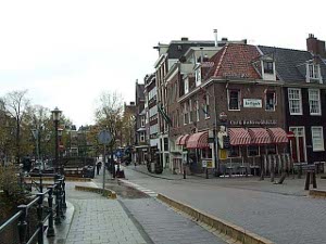 A city scene with brick buildings, tiled roofs, awnings over shop windows