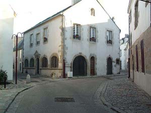 The curving street passes in front of a solid two-story building with arches over all the first floor doors and windows.