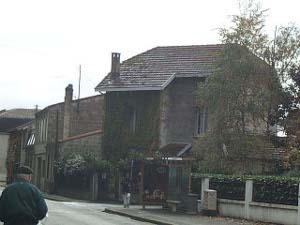 Built of reddish gray stone, this two story house (plus attic) sits on a street corner in the suburb of Bruges, surrounded by greenery