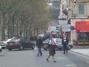 The marchers can barely be seen as a mass of people in the next block, while traffic is directed to turn off and stay away from the demonstration; pedestrians ignore the whole thing