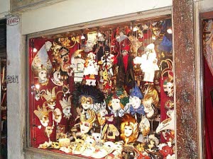 The store window is lined in red cloth and has perhaps 80 shiny masks on display.