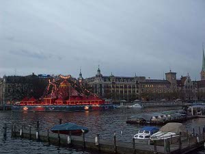 On the shore of the lake, the circus is brightly lit with red and yellow bulbs
