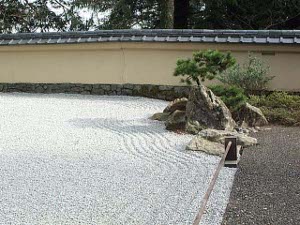 Beautiful fine gravel in a shade of light gray has geen carefully groomed to produces ridges near the edge of the garden where bonsai trees grow
