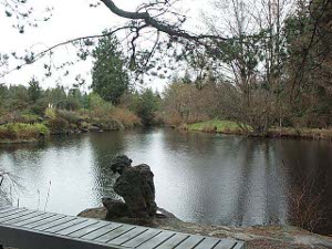 A bronze sculpture rests naturally on a bank at the lakeshore
