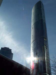 The rays of the sun make a dazzling display on the side of this steel and glass building with the cross-section in the shape of a boat