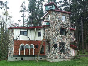 An idiosyncratic home architecture with a stone tower, arches over the windows, pitdppr ;adders. etc.