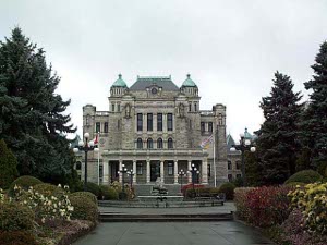 The Provincial Building is an attractive three-story stone structure with green twin domes flanking a central garret; the view is from the gardens at the rear of the building