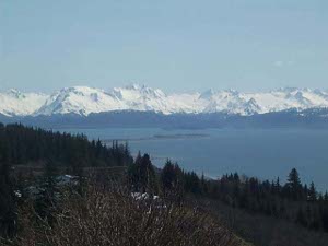 The spit is visible as a slender finger of land jutting out into the bay.  Surrounding the bay are snow-capped mountains.