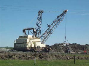 The large white mining machine is many times bigger than the huge dump trucks that are waiting to load up with coal