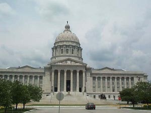 The domed granite capitol has six tall granit pillars in front, at the top of a long row of steps leading to the main entrance