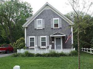 With sides of gray shingles, white shutters and a small picket fence in front, this small holiday cottage is the classic Cape Cod style