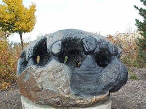 Carved out of a single boulder, the polished heads of people emerge from the stone