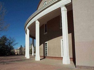 the rounded side of the state capitol, colored tan, with a white-pillared portico