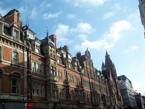 A row of four-story red brick buildings against a blue winter sky with puffs of clouds