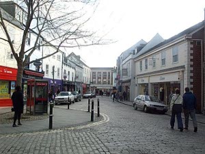 The nicely cobbled street has two story buildings and shops at street level