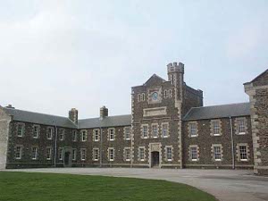 The two story red brick barracks, with stone coigns, extend in a u-shape with a three story central tower and a large paved circular drive in front