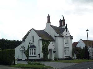 The white two-story brick home has three chimneys and beautiful bay windows, and a long drive.