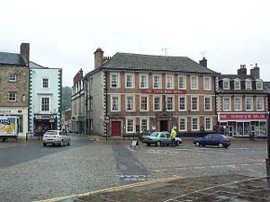 A three story red brick inn in Richmond (the first city of that name) with a couple of cars parked in front