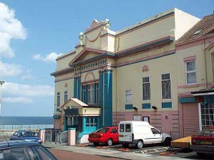 The old beach house is painted cream and pink, with dazzling aquamarine pillars and entrance foyer.  In the background, the North Sea.