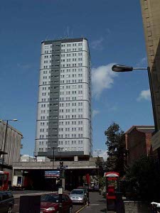 The grey modern skyscraper with curved corners stands about 25 stories tall, and dominates the skyline
