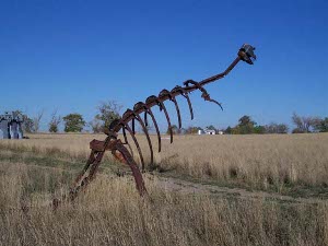 The car frame parts are shaped into ribs and welded to make a passable model of a dinosaur