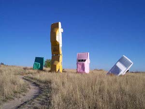 Green, yellow, pink, and white (left to right), the four Fords are buried in the prairie.  The yellow is two cars welded together