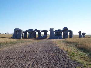 The ring of grey-painted cars planted in the ground is reminiscent of Stonehenge
