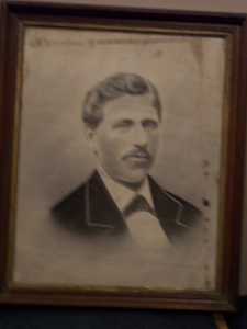 Mr. Pendleton has wavy hair, a moustache, and wears a dark coat with wide lapels, white shirt and tie for this nineteenth century studio portrait.