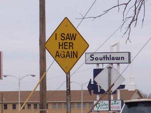 This diamond-shaped yellow sign bears the words, in black capital letters, I SAW HER AGAIN