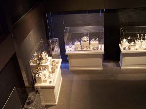 looking down from a balcony at four glass cases of Irish silver table pieces
