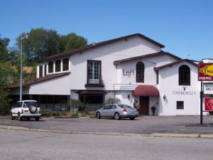 A fine looking two-story restaurant in white stucco with a brown roof, Churchill's in North Bay