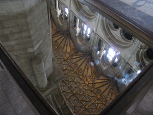 The celing shows an intricate pattern of dark brown and copper brown beams and painting