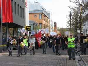 Seven wide, the workers form a column led by a drummer through the streets of town