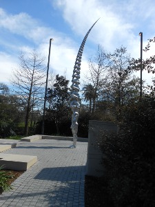The sculpture consists of a couple dozen men, each sitting on top of the next, executed in shiny steel.  The men are in varying poses of thinking, and the overall effect is that of a high narrowing tusk