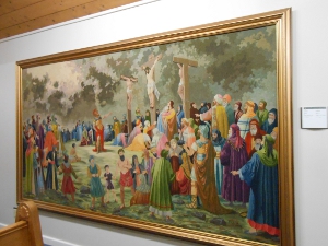 A very wide tapestry of the three crucified figures with many observers dressed in bright colors