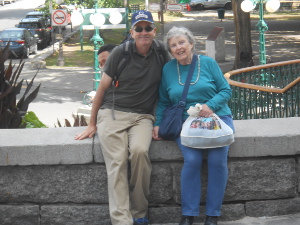 Bryan and Elsa are sitting on a wall, leaning toward one another