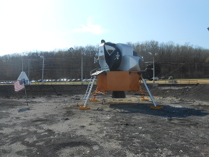 The orange boxy shape is mounted on four legs on a surface supposed to resemble the rocky moonscape.