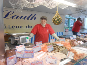 The young lady tending the market wears a red shirt and olive gree hat, and the fish are beautifully arranged on ice.