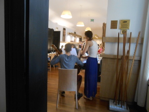 The guitarist is seated while the oboist stands next to him.  The audience is paying attention to breakfast