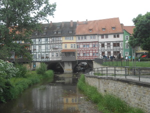 Looking along the river to the arched stone foundations of the bridge with houses built wall to wall along the top of the bridge