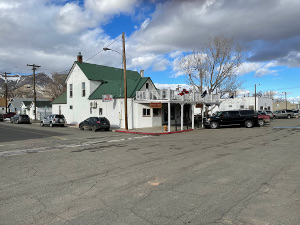 A white two story early twentieth-century building with a green shingle roof, the Martin Hotel is primarily a restaurant today.  The sidewalk is shielded from the sun by a white-railed wooden balcony.